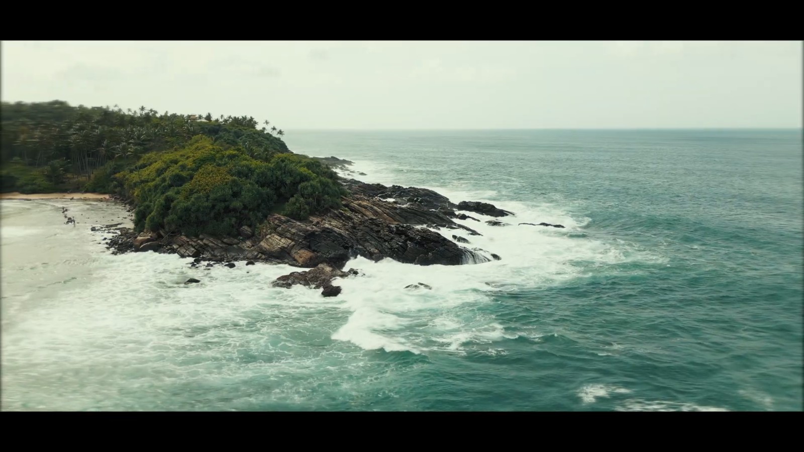 Aerial view of a forested Sri Lankan headland meeting the ocean